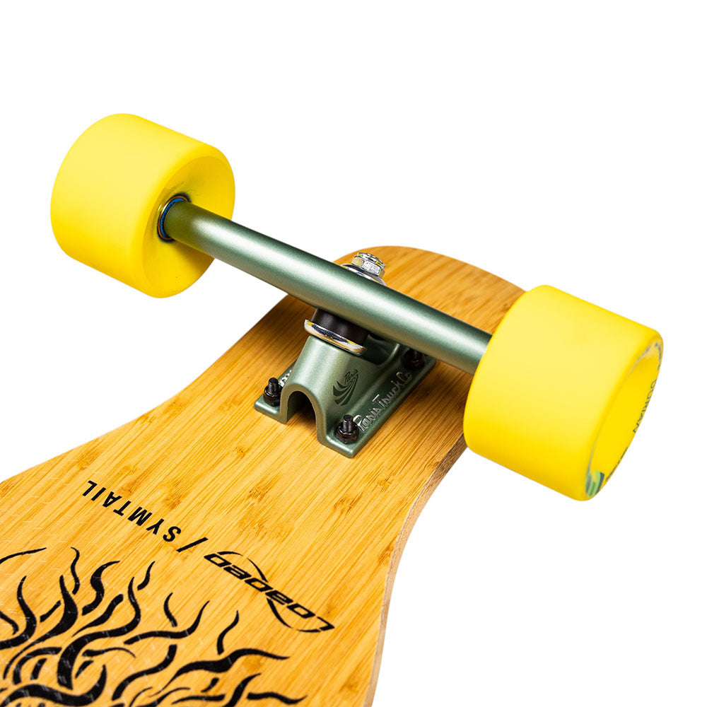 Close-up of the Loaded Symtail 39.5x8.75 Complete Longboard featuring yellow wheels, a green metal truck, and part of a wooden deck with a black flame design—ideal for freestyle dancing—with text: Loaded and SYMMETRICAL.