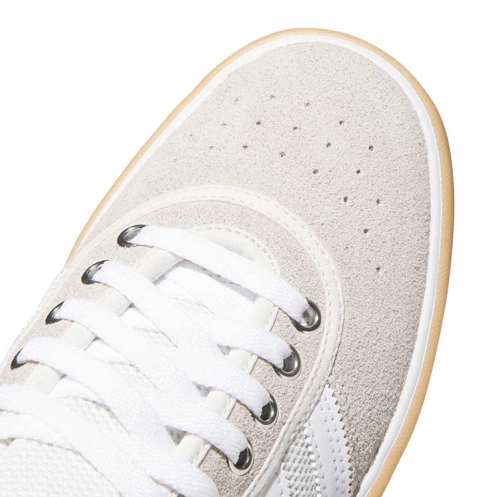 Close-up of the toe area of the Lucas Premiere White Coral HQ7524 Adidas Skateboarding Suede Shoes, showcasing white suede texture, white laces, perforated details, and a light brown rubber sole for a classic skate style.