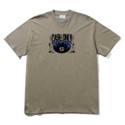 The Metro Tee Stone Cash Only is a beige 6.5oz heavyweight cotton tee with a screenprint of two statues, a city skyline, and "CASH ONLY" above a stylized S logo centered on the front.