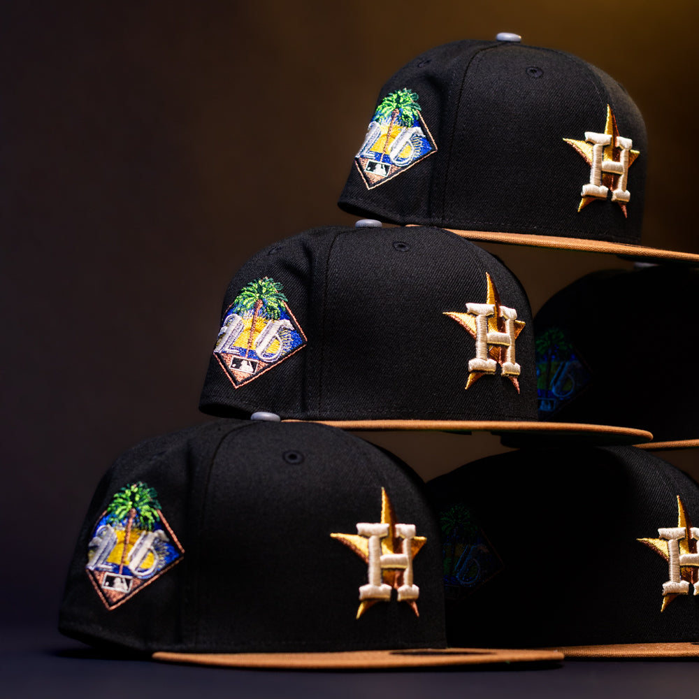 A stack of Midsummer Night 26 Spring Bronze Houston Astros New Era 5950 Fitted hats with black crowns, brown brims, a palm tree patch, and a gold H star logo is displayed against a dark background.
