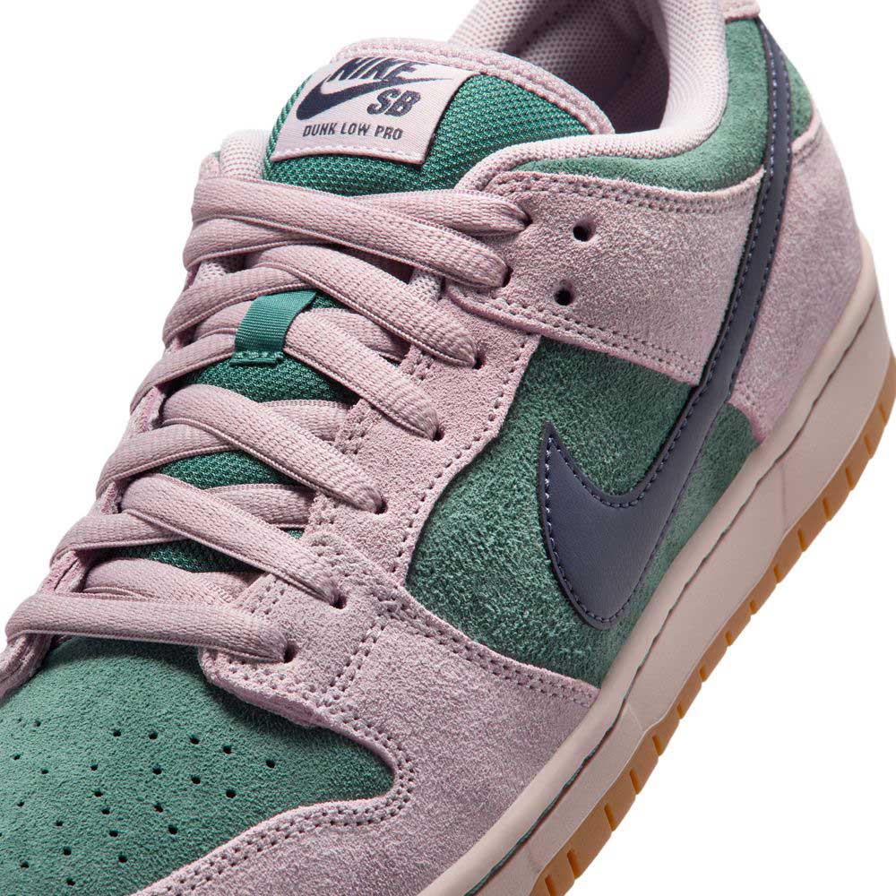 Close-up of the Minereal Slate Dark Raisin Dunk Low Pro HQ1625300 Suede Skateboarding sneaker, featuring dusty pink suede overlays, green panels, blue Swoosh, gum sole, and Nike SB tongue label—timeless style in a classic skate shoe.