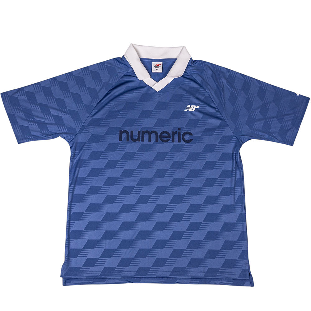 The New Balance Numeric Team Jersey MT61V471ABR is a blue short-sleeve sports jersey with a white collar, geometric pattern, and black "numeric" text and New Balance logo on the chest.