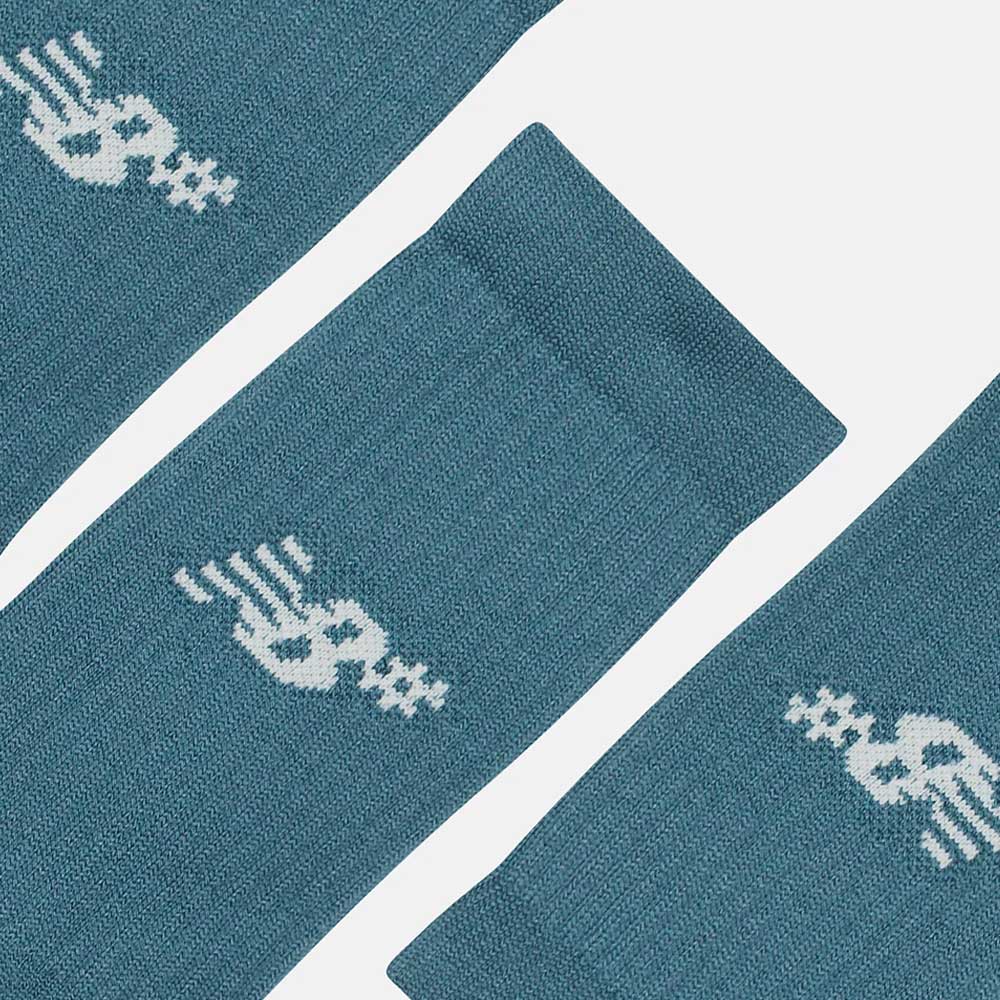 Close-up of New Balance Numeric 3 Pack Socks Salt Water Green AC0048UAAU, featuring a blue color, abstract white winged dollar sign design near the cuffs, and cushioned foot bed, laid out on a plain light background.