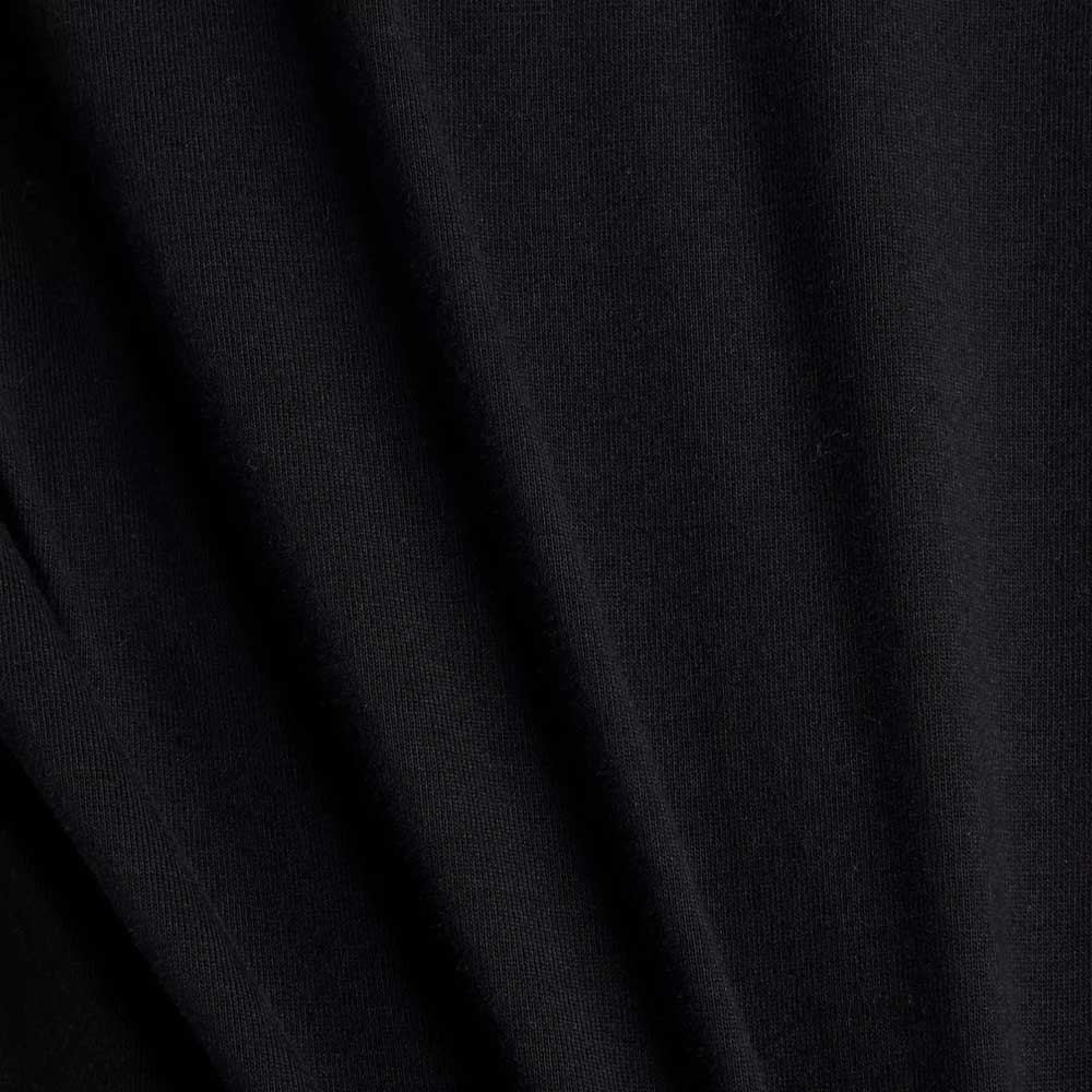 Close-up of black fabric from the New Balance Numeric Small Logo Black Tee MT53706BK, a relaxed fit cotton crewneck with visible diagonal folds and a soft, slightly textured surface.