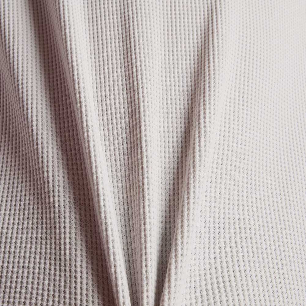 Close-up of the New Balance Numeric Waffle Knit Tee MT51958GYM, featuring light-colored, textured waffle knit fabric with a honeycomb pattern and gentle vertical folds.