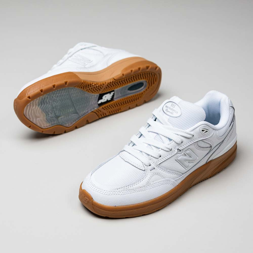A pair of 933 WWB White Black Andrew Reynolds New Balance Numeric Suede Skateboarding Shoes with brown gum soles displayed on a light plain background—one shoe upright to show side and top, the other on its side to reveal the sole.
