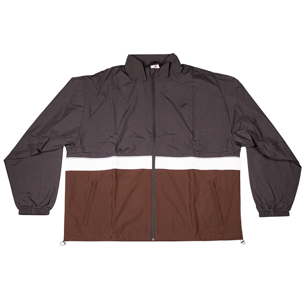 The New Balance Numeric Jacket MJ61W4XCABR features a brown and dark gray color-block design, white chest stripe, zipper closure, long sleeves with elastic cuffs, and durable ripstop fabric.