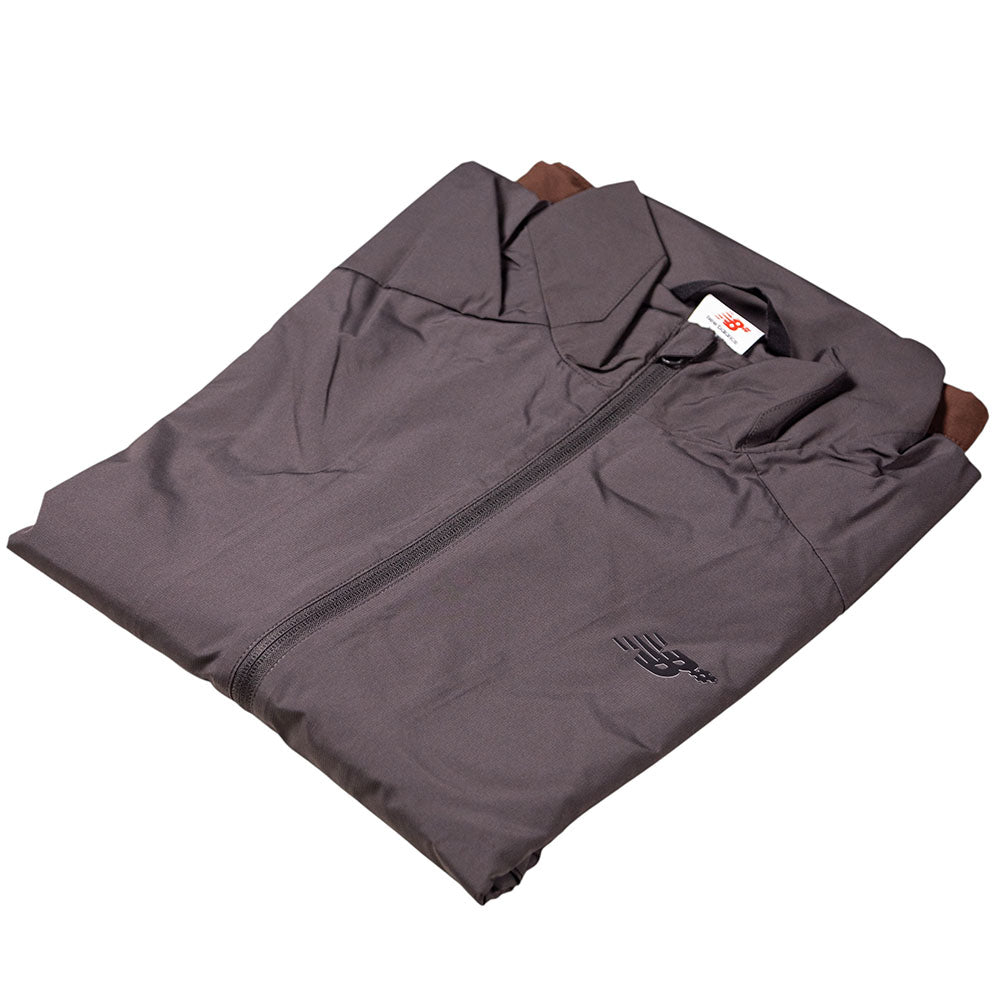A folded gray New Balance Numeric Jacket MJ61W4XCABR with a collar, small black chest logo, visible neck label, and made from durable ripstop fabric.