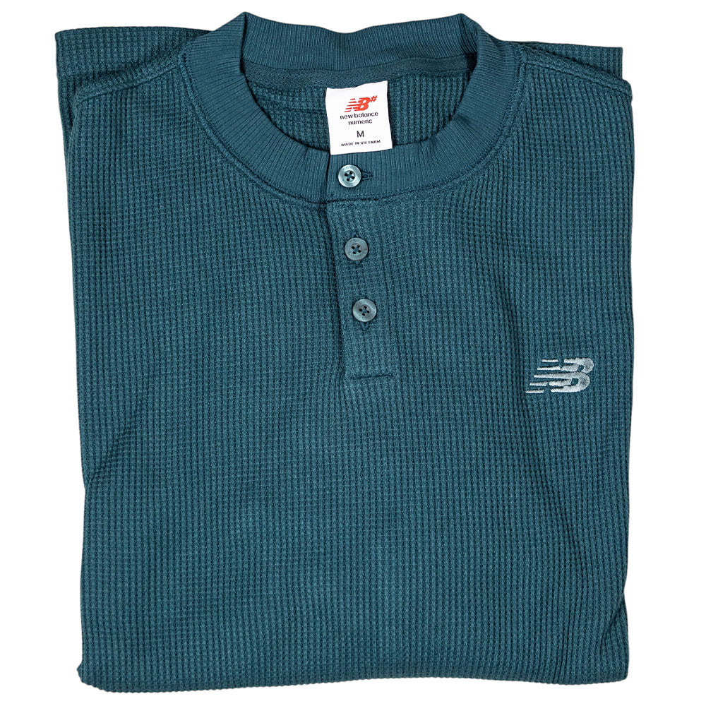 The New Balance Numeric Waffle Knit Tee MT51958AAV is a folded teal long sleeve Henley with three buttons and an embroidered chest logo—ideal as a thermal top for cool weather.