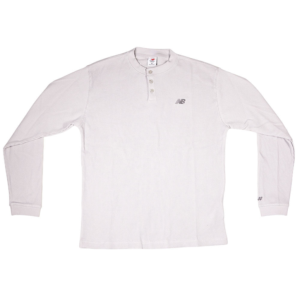 The New Balance Numeric Waffle Knit Tee MT51958GYM is a light gray, long-sleeve thermal with a partial button-up collar, ribbed cuffs, and an embroidered New Balance logo on the left chest, shown laid flat on a white background.