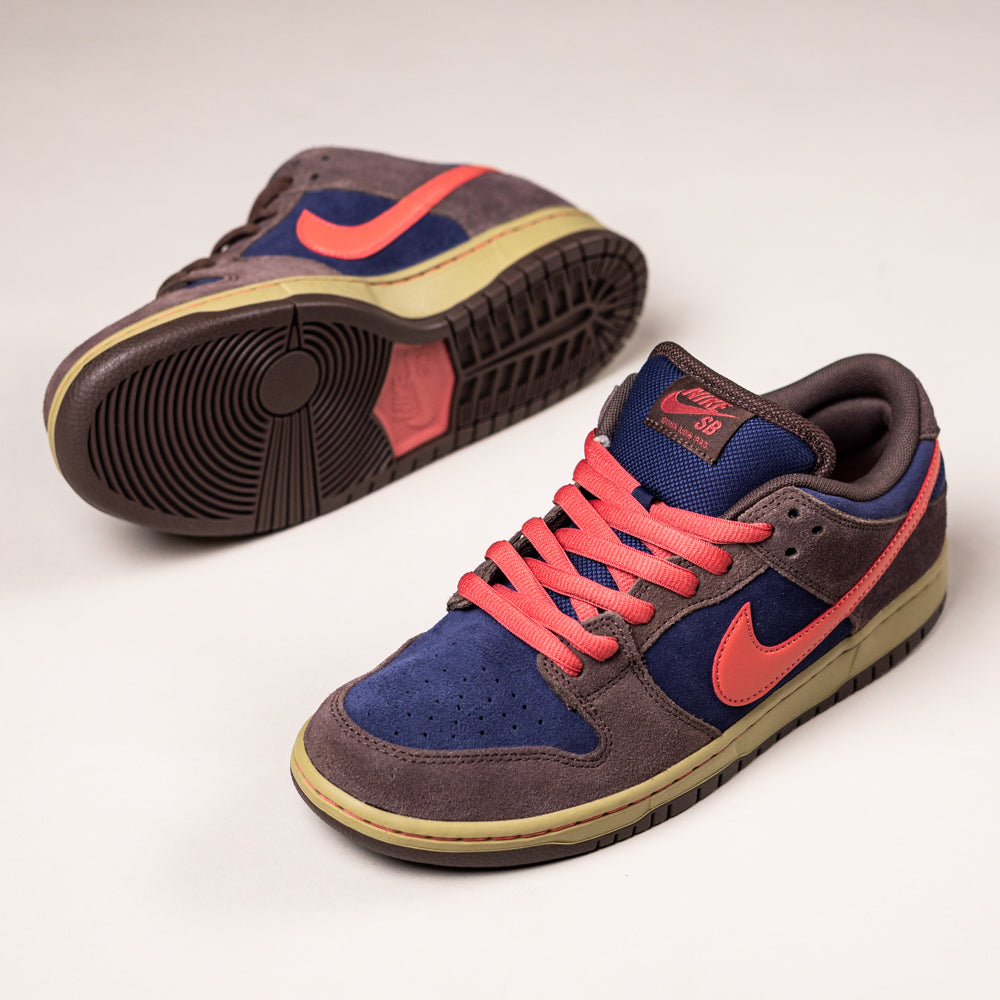 The Baroque Brown Adobe Midnight Navy Dunk Low Pro HQ1625200 Nike SB Suede Shoes feature dark brown, navy, and olive panels with bright pink laces and Swooshes, offering a bold update to the classic basketball sneaker.