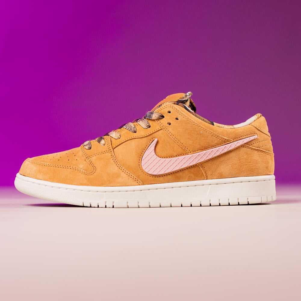 The READ BELOW the BUTTON RAFFLE Nike SB Brew and Biscuits Dunk Low features tan suede, a light pink swoosh, and a white sole. Enter Southside Skatepark's raffle for your chance to score this exclusive style against a purple gradient backdrop.