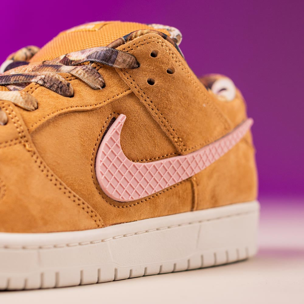 Close-up of the READ BELOW the BUTTON RAFFLE Nike SB Brew and Biscuits Dunk Low, featuring tan suede, a textured pink Swoosh, white sole, and plaid laces—ideal for your next Southside Skatepark raffle entry.