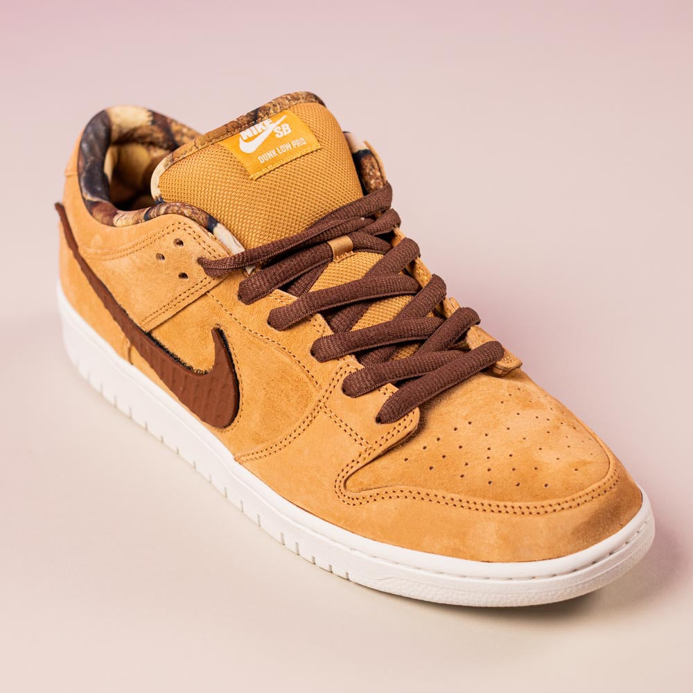 The READ BELOW the BUTTON RAFFLE Nike SB Brew and Biscuits Dunk Low features tan suede, brown laces, a brown swoosh, and a white sole, shown on a light pink background—ideal for your next Southside Skatepark raffle entry.