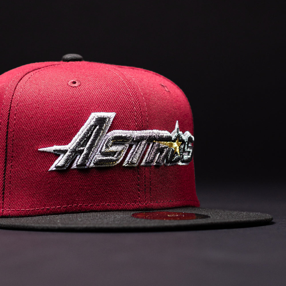 A Bloodline OG Cardinal Red Houston Astros New Era 5950 Fitted Hat in red and black, featuring “Astros” and a yellow star embroidered on the front, set against a dark background.
