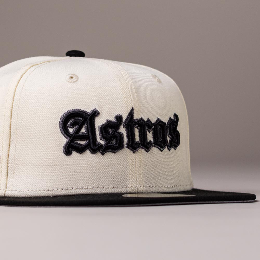 Showcasing classic Houston Astros pride, the Straight Outta Southside OG Chrome Black Houston Astros New Era Hat 5950 Fitted features a white crown with a black brim. The word “Astros” is embroidered in bold, black Gothic-style lettering on the front. This fitted cap is displayed against a plain, light-colored background.