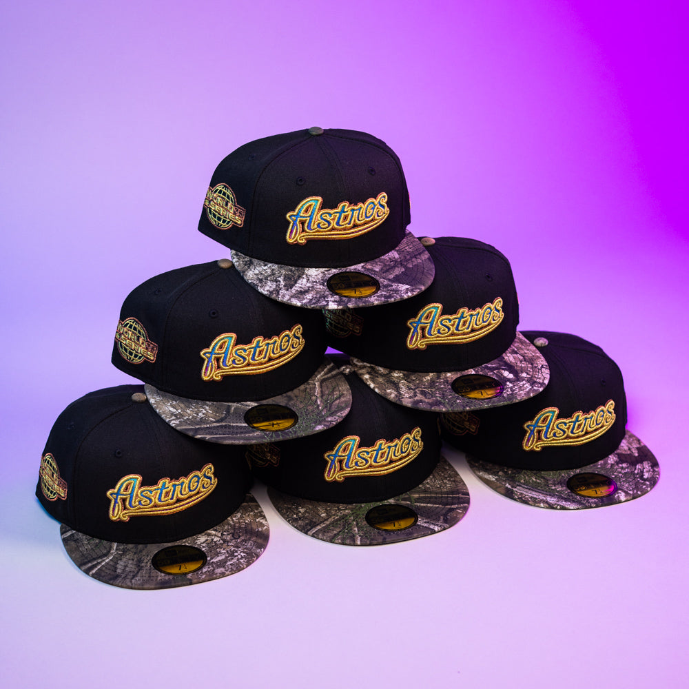 Six Oil Spill WS05 Houston Astros New Era Hat 5950 Fitted caps with black crowns and camo brims are stacked pyramid-style on a purple gradient background. Each features a gold Astros logo and commemorative side patch.