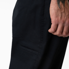 A close-up of a wrist tattooed hand beside the side pocket of the P415314 Mike Anderson Black Twill Pant by Dickies Skateboarding, highlighting its simple stitching and durable flex fabric.