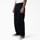 A person wears durable black pants—P415314 Mike Anderson Black Twill Pant Dickies Skateboarding—a white shirt, and black-and-white sneakers, standing against a plain white background. Only the lower half of the body is visible.