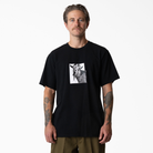 A man with tattooed arms wears the P415867 Mike Anderson Goat Black Tee from Dickies Skateboarding, standing facing forward against a plain white background.