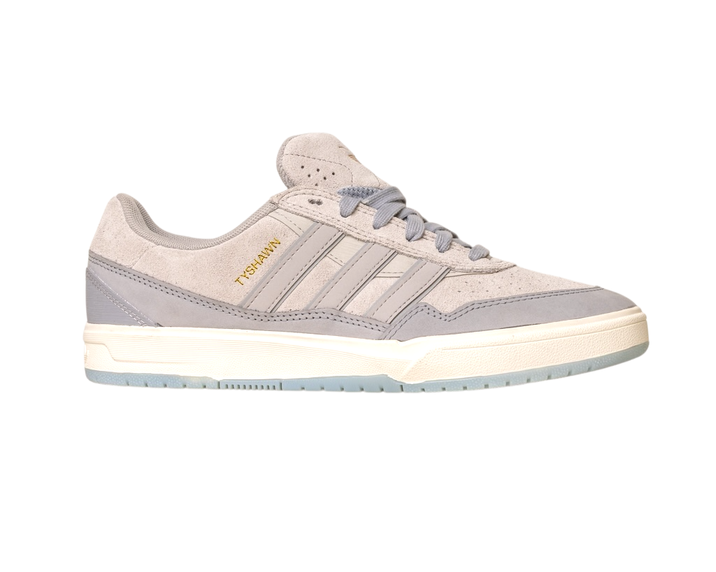 The JI0848 Granite White Tyshawn 2 II Adidas Skateboarding Shoes feature light gray suede and leather, three stripes, gold TYSHAWN branding, a white sole with a translucent light blue bottom, and are inspired by the Tyshawn II skateboard design.