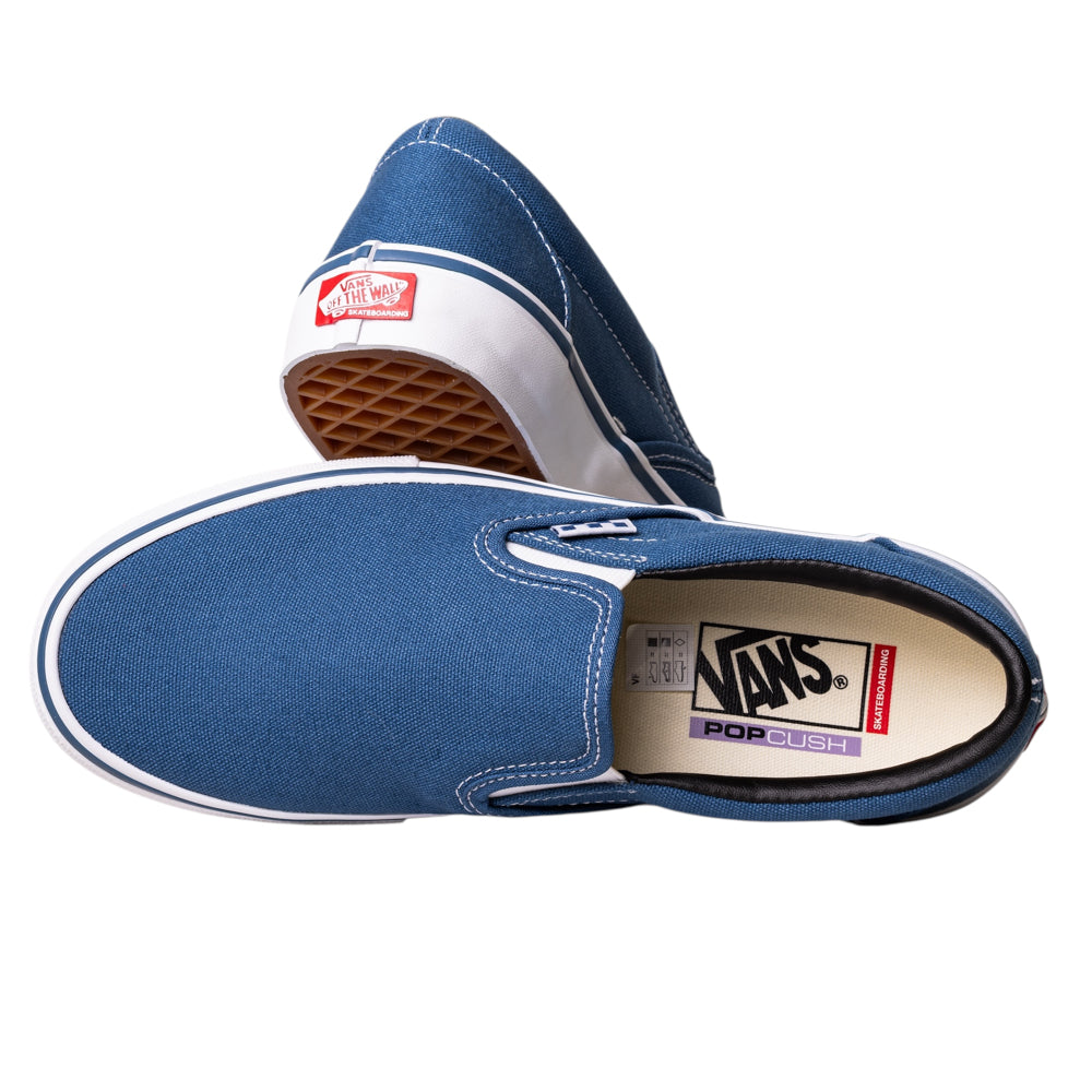 A pair of VN0A5FCANVY1 Navy Skate Slip On Vans Canvas Shoes in blue with white soles. One shoe is on its side, revealing the waffle sole; the other is upright, showing the Vans logo and POPCUSH cushioning for comfort.