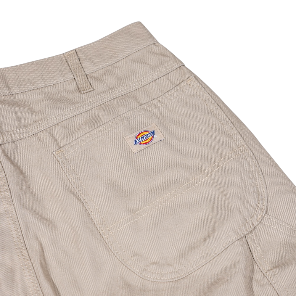 Close-up of the back pocket on the 1939 Rinsed Desert Sand Duck Relaxed Utility Jean Denim Pant by Dickies Skateboarding, featuring a sturdy, textured fabric and a small Dickies logo patch—ideal for men's workwear and relaxed fit carpenter styles.