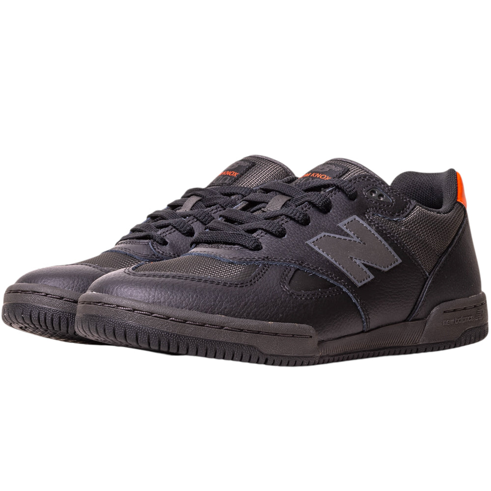 The 600TOO Black Orange Tom Knox New Balance Numeric Leather Skateboarding Shoes feature black uppers, gray N logos, black laces, textured soles, an orange heel accent, and responsive FuelCell foam, shown on a white background.