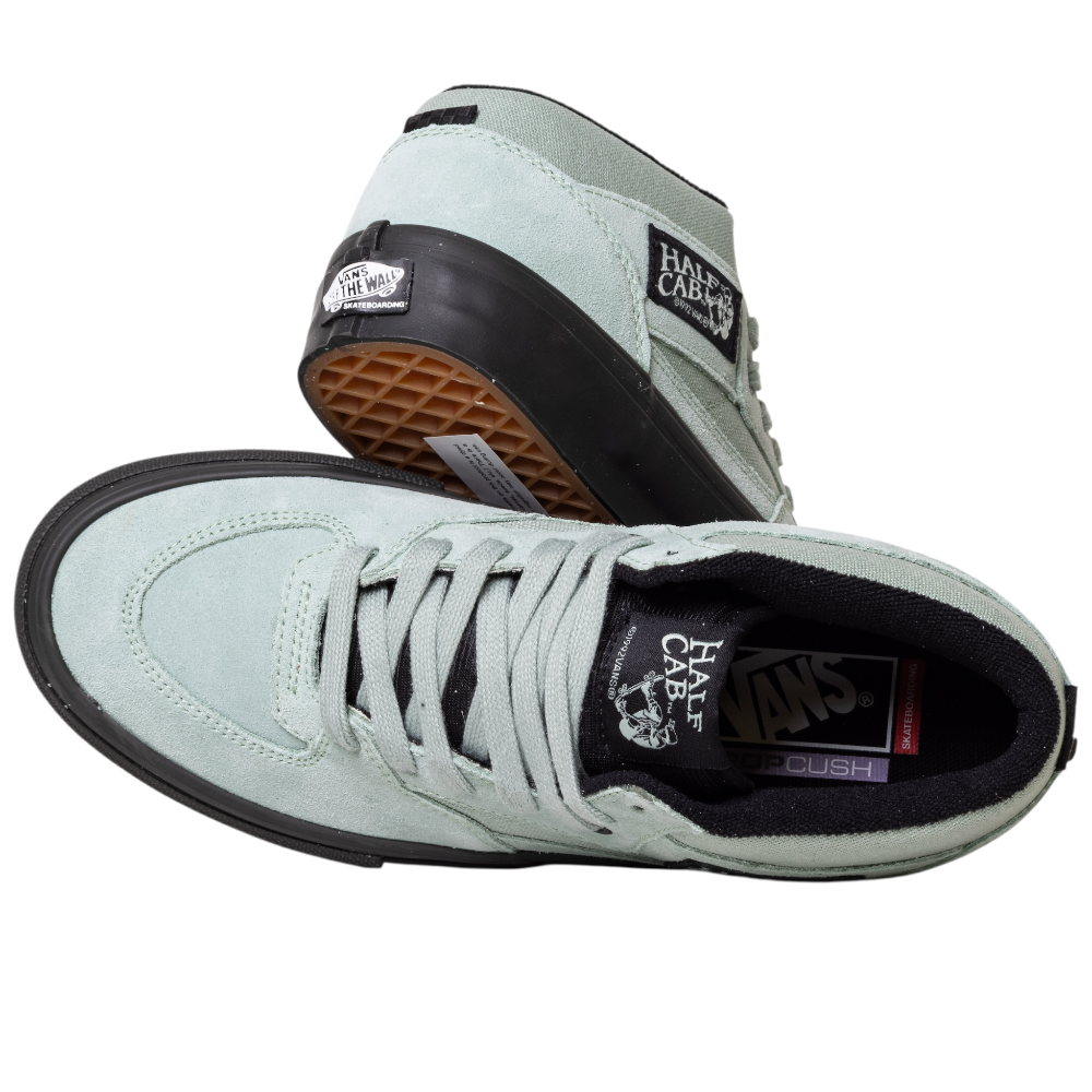 A pair of VN0A5FCDEMW1 Gray Olive Suede Skate Half Cab Vans shoes with black soles. One shoe sits upright, highlighting the top and laces; the other is angled to show the sole, PopCush cushioning, and tongue logo patch.