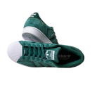 The JQ1103 Core Green White Superstar ADV Adidas Skateboarding Suede Shoes feature green suede, white shell toes, and soles. One shoe stands upright, while the other lies sideways, highlighting the Adidas logo and signature stripes.