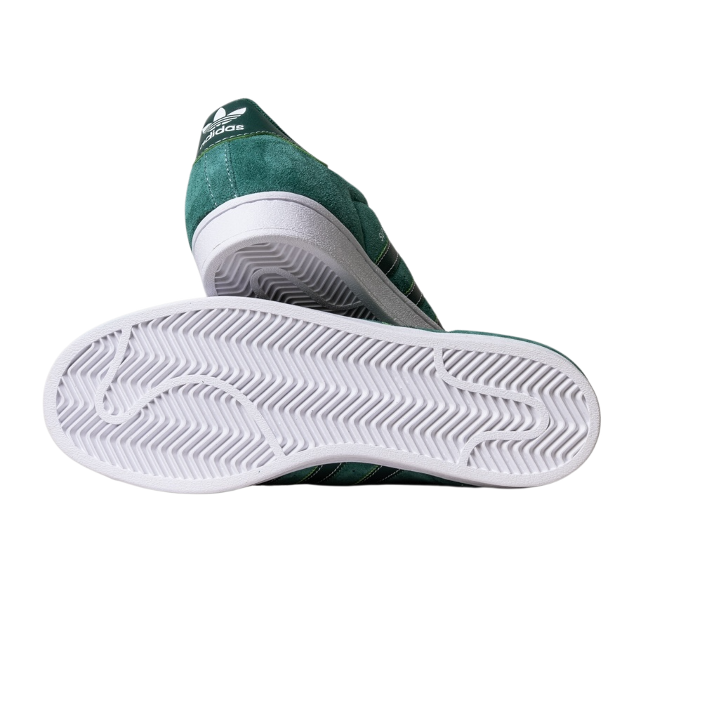 The JQ1103 Core Green White Superstar ADV Adidas Skateboarding suede shoes feature white stripes, a white sole with a zigzag tread for grip, and heel branding—shown from the side and bottom to highlight skate-friendly details.