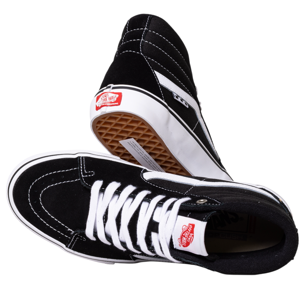 A pair of VN0A5FCCY281 Black White Skate SK8-HI Suede Vans shoes with white laces, stitching, signature side stripe, and gum waffle sole. One shoe stands upright; the other lies on its side.