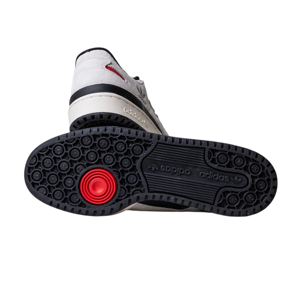 A close-up of the JP6094 Cry White Core Black Forum 84 Low Adidas Skateboarding Suede Shoes highlights the black sole with circular treads, a red detail near the heel, a central Adidas logo, and a light suede upper.