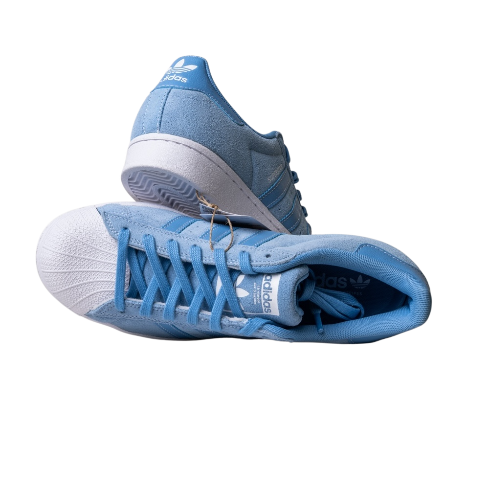 The JQ1102 Light Blue White Superstar ADV Adidas Skateboarding suede shoes are shown against a white background. One shoe stands upright, the other lies on its side, both featuring white soles and Adidas logos on the tongue and heel.