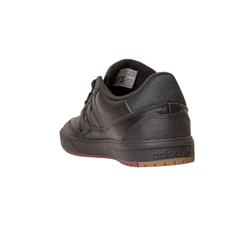 The Tyshawn 2 II Adidas Skateboarding Shoes, shown in Core Black/Core Green leather, are viewed from the back and side, highlighting the heel, brown-edged sole, stitched leather, and embossed Adidas logo on the heel.