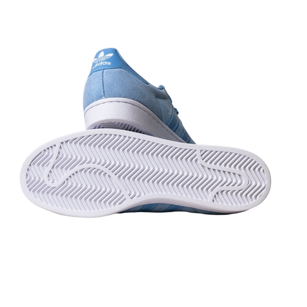 The JQ1102 Light Blue White Superstar ADV Adidas Skateboarding Suede Shoe is shown with its white sole and herringbone tread pattern facing upward. The Adidas logo appears on the heel, set against a plain white background.