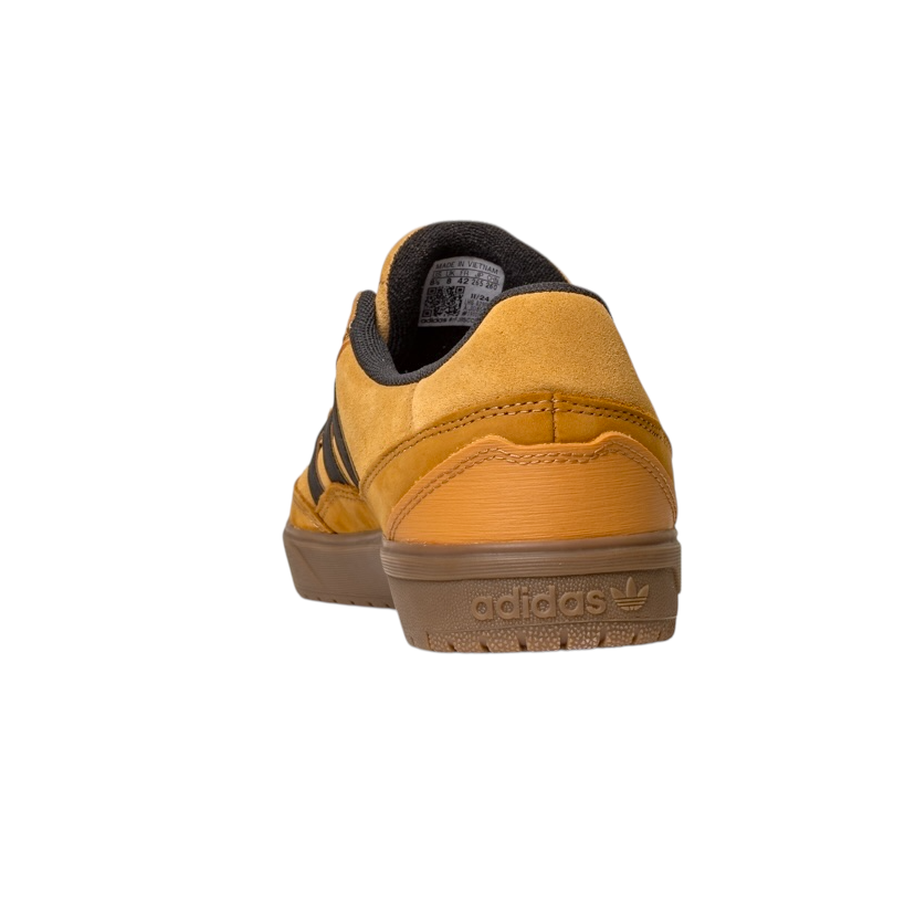 The JI0851 Mesa Black Gum Tyshawn 2 Adidas skateboarding shoe, shown from the back on a white background, features mustard yellow suede, black stripes, a brown cupsole rubber sole, and is inspired by the Tyshawn II design.