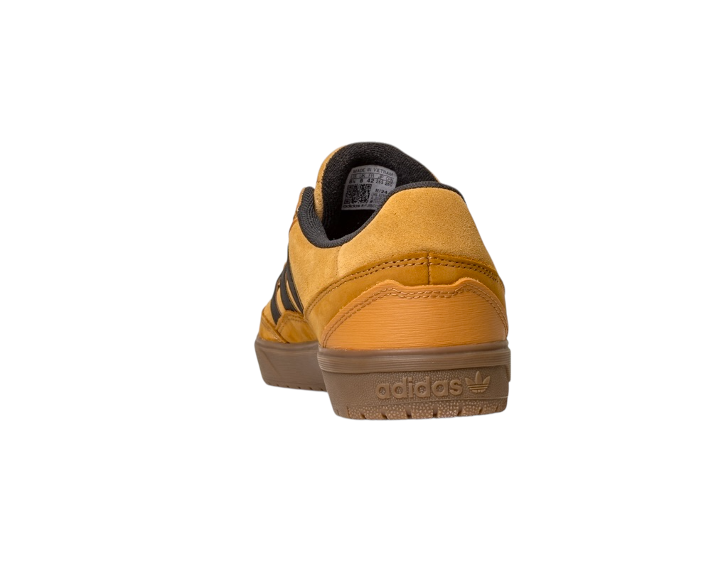 The JI0851 Mesa Black Gum Tyshawn 2 Adidas skateboarding shoe, shown from the back on a white background, features mustard yellow suede, black stripes, a brown cupsole rubber sole, and is inspired by the Tyshawn II design.
