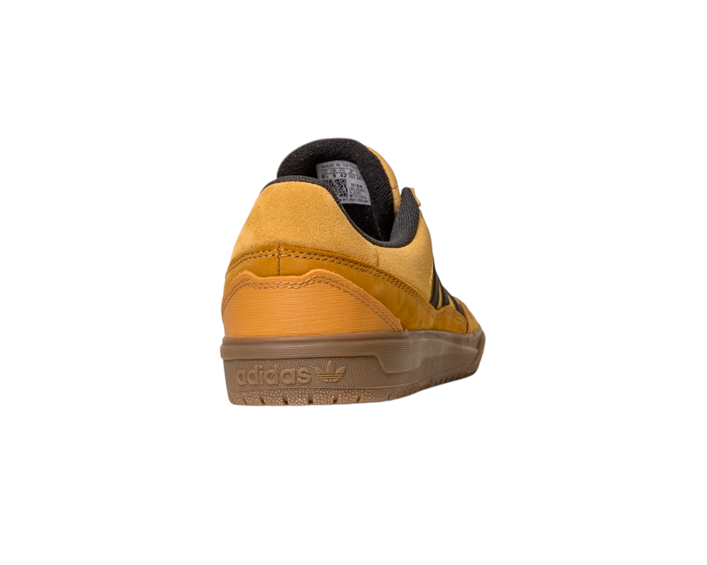 The JI0851 Mesa Black Gum Tyshawn 2 II Adidas leather suede skateboarding shoe, shown from the back-left, features a yellow suede upper, black lining, and an embossed Adidas logo on its translucent brown rubber cupsole.