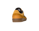 The JI0851 Mesa Black Gum Tyshawn 2 II Adidas leather suede skateboarding shoe, shown from the back-left, features a yellow suede upper, black lining, and an embossed Adidas logo on its translucent brown rubber cupsole.