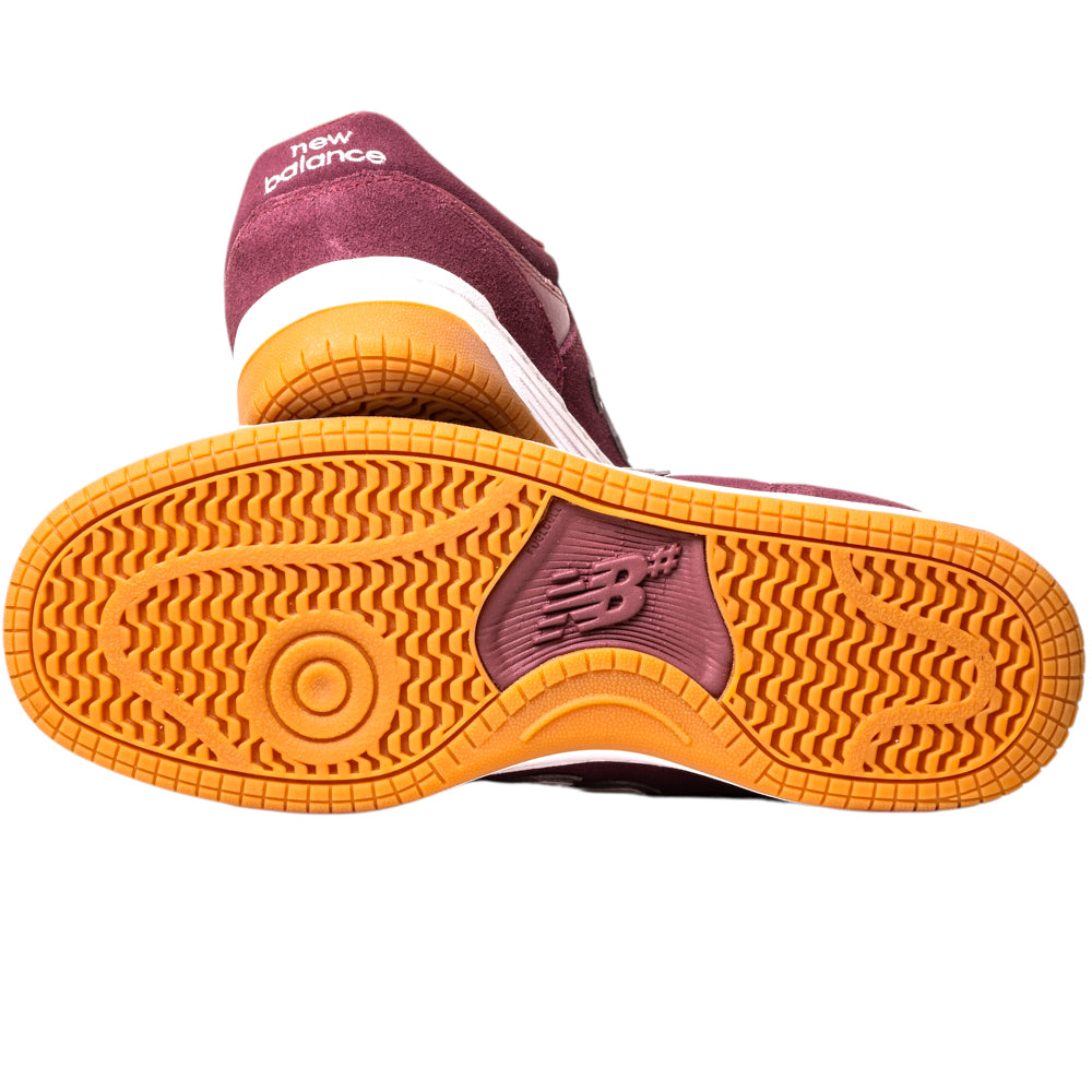 The 480PRO Monarch Burgundy New Balance Numeric Suede Skateboarding Shoes feature a maroon upper and orange/white sole, with one shoe showing its textured tread and the other upright, highlighting the New Balance logo—ideal for fans of heritage styles.