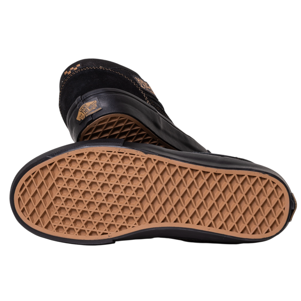 A pair of VN000E8QGSL Black Black Brown Suede Skate Half Cab Vans Shoes with tan waffle-patterned soles—one on its side showing the sole, the other upright behind it. The heel's brand logo adds a classic streetwear touch.