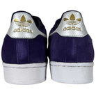 Back view of Purple Zero Gold Superstar ADV Adidas Skateboarding Suede Shoes with metallic gold heel tabs, reflective badging, Adidas logo and text. White midsoles and outsoles are also visible.