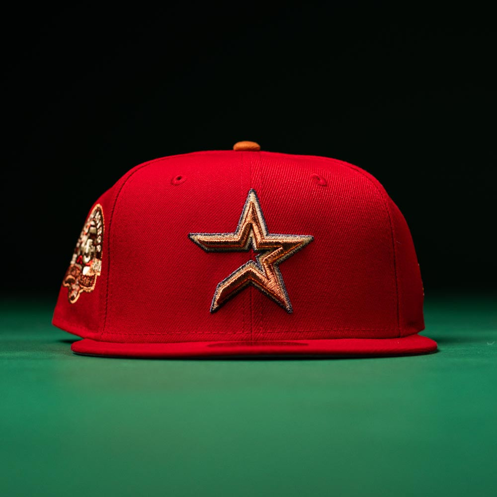 A Rusty Screw OG Scarlet Copper Houston Astros New Era 5950 Fitted hat featuring a gold and black outlined star emblem on the front and a commemorative patch on the left side, displayed against a dark green background.