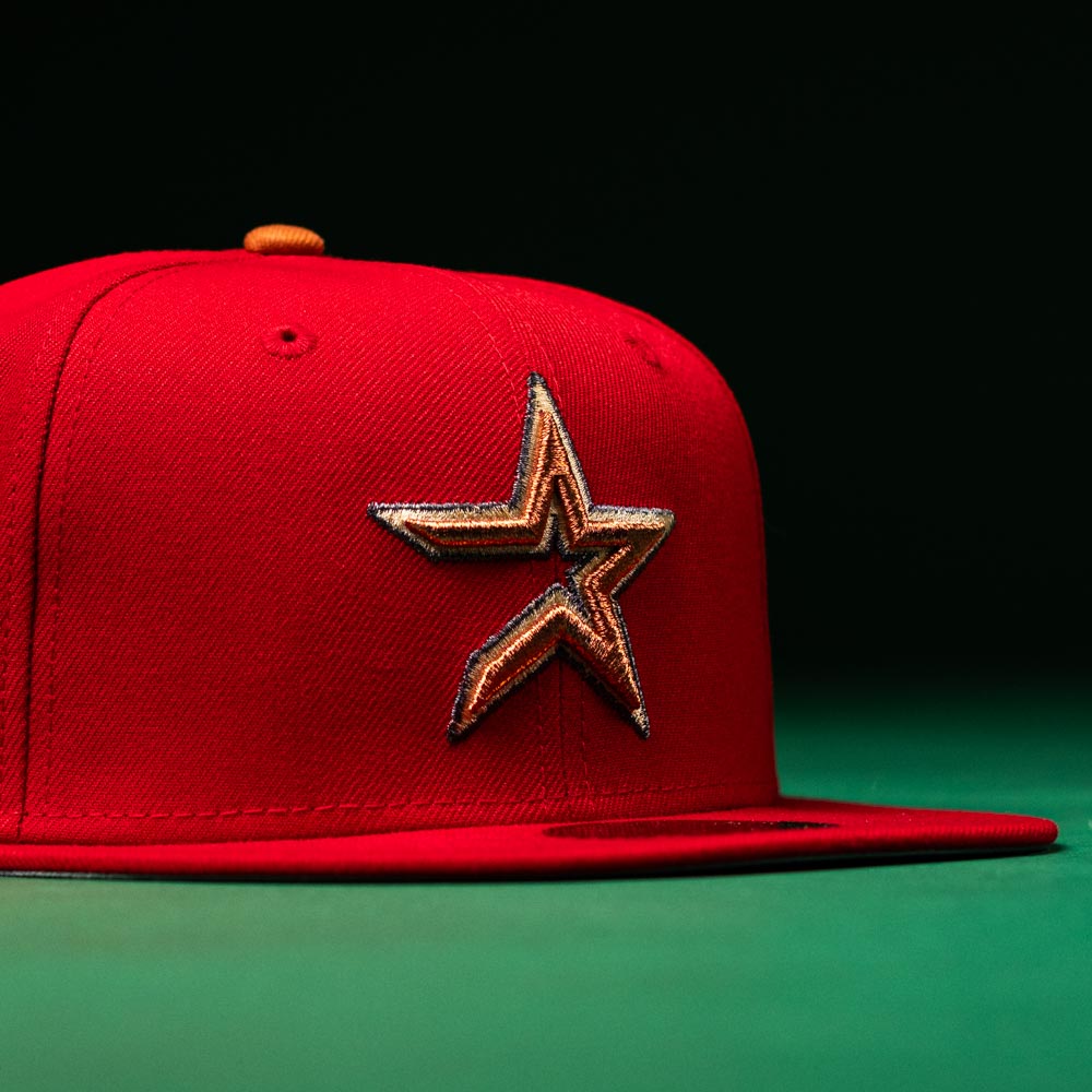 Introducing the Rusty Screw OG Scarlet Copper Houston Astros New Era Hat 5950 Fitted—a striking red fitted cap with a prominent embroidered gold and black star logo on the front, perfectly embodying classic Astros style against a dark green and black backdrop.