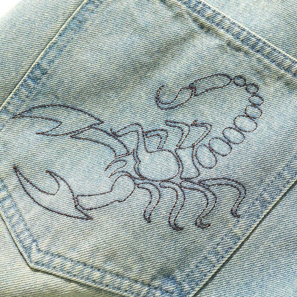 Close-up of the Scorpion Stitch Tinted Light Blue Denim Jeans by Butter Goods, featuring an embroidered scorpion on the patch pocket—ideal for those who love unique, baggy fit denim.
