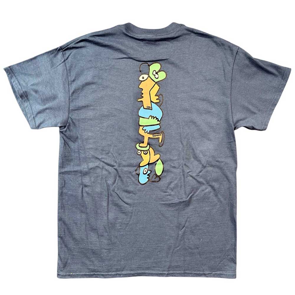 The Sebo Walker x Southside Skatepark Blueberry Tee features a dark gray color and a vibrant, cartoon-style back graphic of four abstract faces stacked vertically in yellow, green, and blue—a Southside Skatepark exclusive.