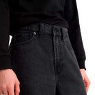 A person wearing Skate Check 5 Loose Shorts in black denim by Vans Skateboarding and a black long-sleeve shirt, shown from waist to mid-thigh against a plain background.