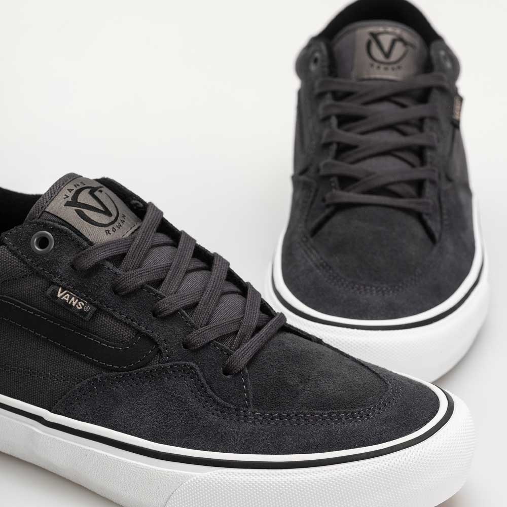 A close-up of Skate Rowan Asphalt White VN0A5JICRP9 suede Vans shoes features black laces, white soles, and a Vans logo patch on the tongue. These Rowan Zorilla skate sneakers are displayed against a white background.