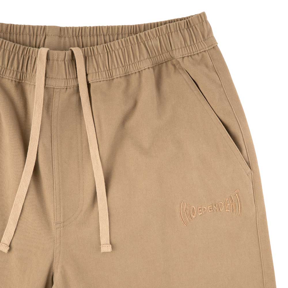 Close-up of Span Elastic Waist Shorts Khaki Bottom Mens Independent, featuring a baggy fit, long inseam, elastic waist with drawstring, side pocket, and "Independent" embroidered in matching tan near the pocket.